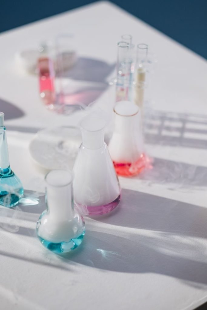 High-angle view of colorful laboratory flasks with evaporating liquids on a white surface.